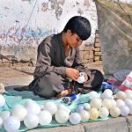 A young vendor repairs an LED bulb at his roadside stall in the provincial capital