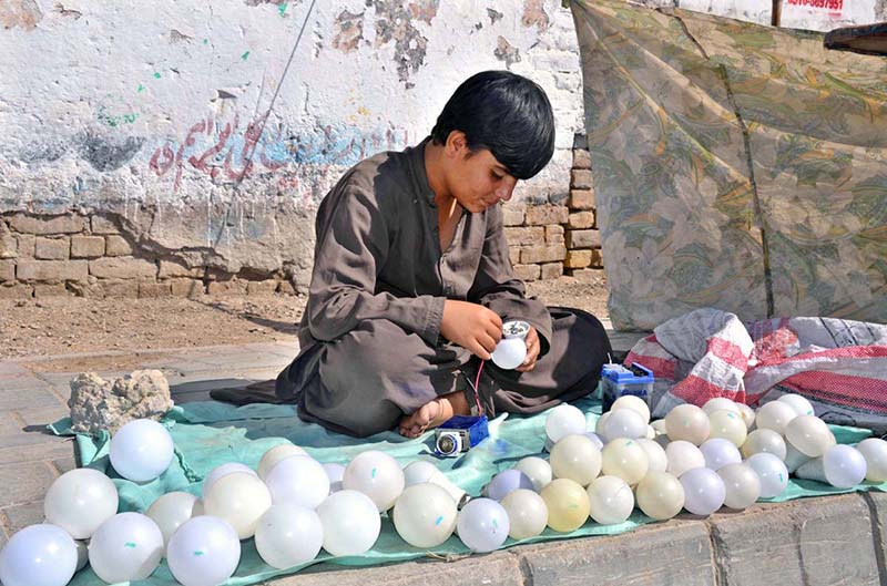 A young vendor repairs an LED bulb at his roadside stall in the provincial capital