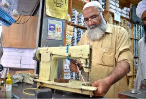 A man is crafting baskets, hand fans, and screens by hand from dried date palm leaves at his workplace