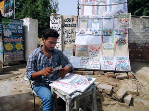 A man prepares engraved name slabs for graves outside a graveyard