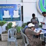 A large number of motorcyclists stand in a queue to receive tokens for subsidized petrol under the Prime Minister's Fuel Relief Scheme in Latifabad