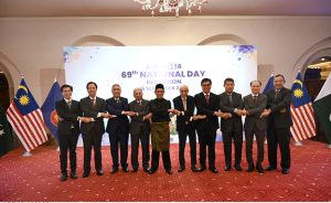 Federal Minister for Board of Investment Qaiser Ahmed Shaikh, Federal Minister for National Food Security and Research Rana Tanveer Hussain, Malaysian High Commissioner Dato' Mohammad Azhar Mazlan, and other dignitaries clasp hands in a gesture of solidarity, posing together as Malaysia's 69th National Day is celebrated at a local hotel