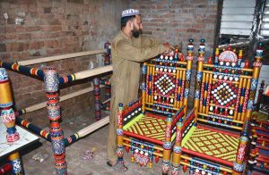 A carpenter makes wooden furniture for customers at his workshop.