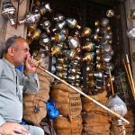 A shopkeeper smokes a hookah while displaying traditional hookah components (chilam) at his shop in the provincial capital