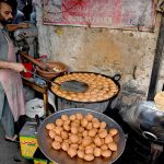 A vendor making local food item Laddu Peethi on the roadside setup outside at Dehli Gate