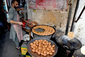 A vendor making local food item Laddu Peethi on the roadside setup outside at Dehli Gate