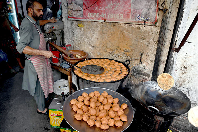 A vendor making local food item Laddu Peethi on the roadside setup outside at Dehli Gate