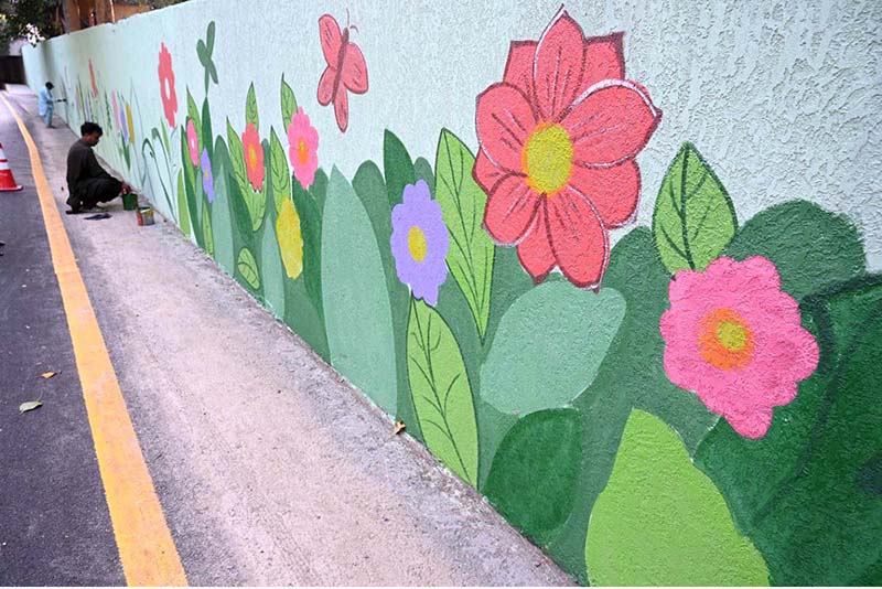 An artist paints the wall of Muslim town under pass canal road during the development and beauty work in the city