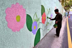 An artist paints the wall of Muslim town under pass canal road during the development and beauty work in the city