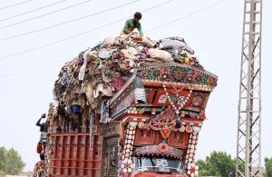 A gypsy man collects valuables from waste loaded on a truck at Mohenjo-Daro Airport Road.