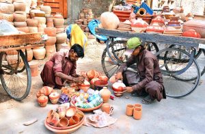 Workers are busy coloring the clay-made pots for selling at Kumhar Para