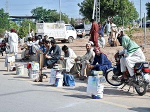 - Labourers sit along the roadside with their tools, waiting to be hired for daily work at the PWD Interchange.