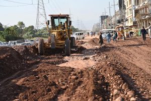 Workers weld a large gas pipeline in a deep trench as a crane holds the pipe in position during repair work in the Federal Capital
