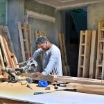 A carpenter is busy cutting wood to prepare door frames for a house at a construction site