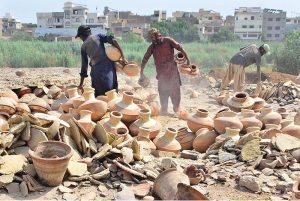 Labourers are busy shifting clay made stuff after preparing at their workplace.