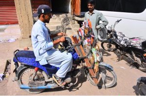 A blacksmith is sharpening customers' knives using a mobile service in the Dadan Shah Colony area.