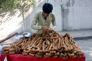 A young vendor arranges to sell dried figs on his handcart by the roadside in provincial capital.