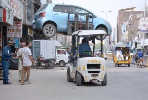 Traffic warden removing the wrong parked car with the help of a forklift