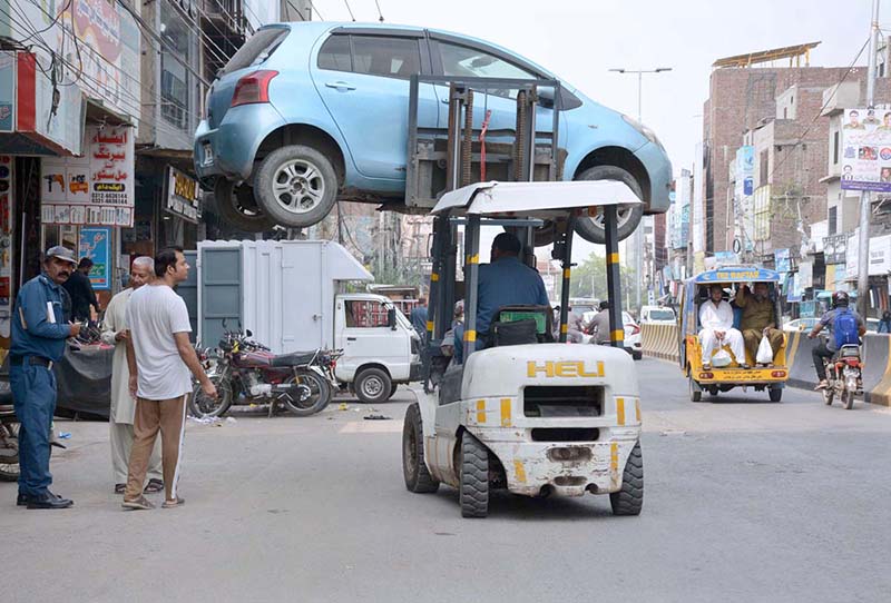 Traffic warden removing the wrong parked car with the help of a forklift