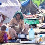 A gypsy woman busy in washing pots outside her hut at Makki Shah area