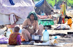 A gypsy woman busy in washing pots outside her hut at Makki Shah area