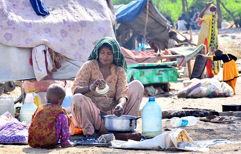 A gypsy woman busy in washing pots outside her hut at Makki Shah area