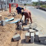 Labourers install concrete blocks along the roadside as part of ongoing road and drainage development work