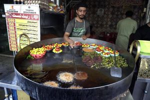 A vendor lifts a freshly fried chapli kebab from sizzling oil to attract customers at his shop in Banni Chowk.