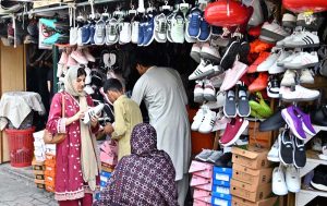 A woman is selecting and purchasing shoes from a stall in Sunday Bazaar at Peshawar Mor in the Federal Capital