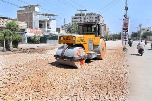 A labourer is busy levelling a new road with the help of a road roller during road construction work at Latifabad Road.