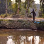 A man throws fishing net into the Noubahar Canal to catch fish
