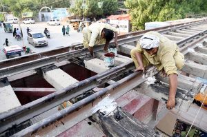 Railway workers busy in maintenance work on the railway track bridge near Municipal Higher Secondary School