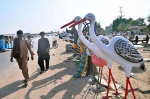 A vendor is displaying decorative statues representing different animals and birds to attract customers at Qasimabad Road.
