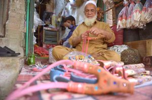 A traditional wooden slingshot maker prepares and decorates handmade slingshots at his shop, showcasing a centuries-old local craft.