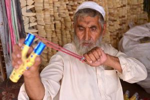 A traditional wooden slingshot maker prepares and decorates handmade slingshots at his shop, showcasing a centuries-old local craft.