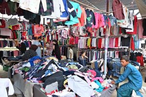 A woman is selecting and purchasing shoes from a stall in Sunday Bazaar at Peshawar Mor in the Federal Capital