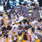 Vendors displaying shoes to attract the customers at stall in Sunday Bazaar