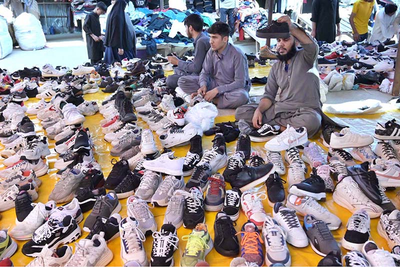 Vendors displaying shoes to attract the customers at stall in Sunday Bazaar