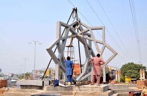 Labourers are busy installing a large geometric steel structure at Model Town Chowk during ongoing urban development work in the city.