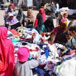 Women busy in selecting and purchasing cloth pieces from vendor at cloth market road