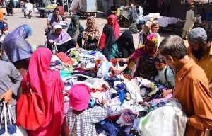 Women busy in selecting and purchasing cloth pieces from vendor at cloth market road