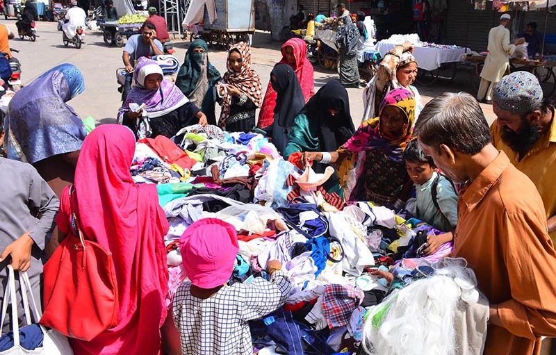 Women busy in selecting and purchasing cloth pieces from vendor at cloth market road