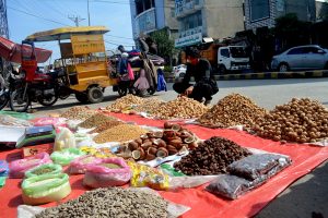 A customer purchases dry fruits from a roadside vendor at a weekly Friday bazaar.