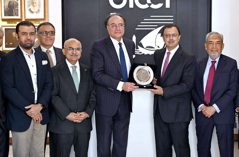 Report: Federal Minister for Finance and Revenue Senator Muhammad Aurangzeb receives a souvenir during a meeting at the Overseas Investors Chamber of Commerce and Industry (OICCI) office