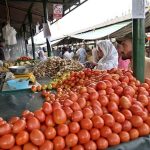 People purchase tomatoes and ginger from vendors stall at the Aabpara weekly Bazaar in the Federal Capital