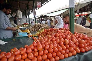 People purchase tomatoes and ginger from vendors stall at the Aabpara weekly Bazaar in the Federal Capital