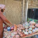 A vendor arranging and displaying the different kinds of clay pots on his handcart in the street to attract the customers
