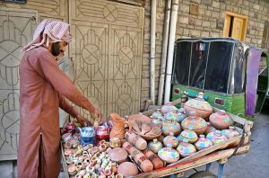 A vendor arranging and displaying the different kinds of clay pots on his handcart in the street to attract the customers
