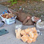 An elderly vendor taking a nap on the footpath in the shade of a tree in the Federal Capital