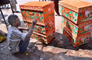 An artist paints iceboxes used for preparing and storing kulfi at his workplace on Fort Road.